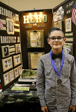 A young student poses with his winning project