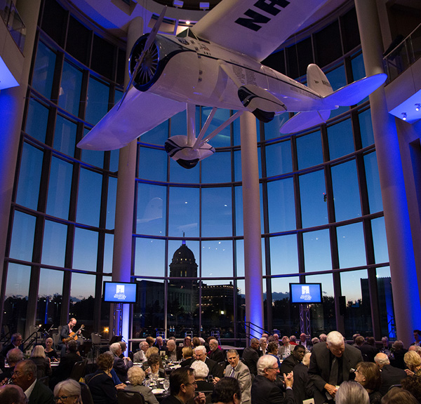 Tables and chairs in the History Center atrium. The capitol at sunset is visible through the window.