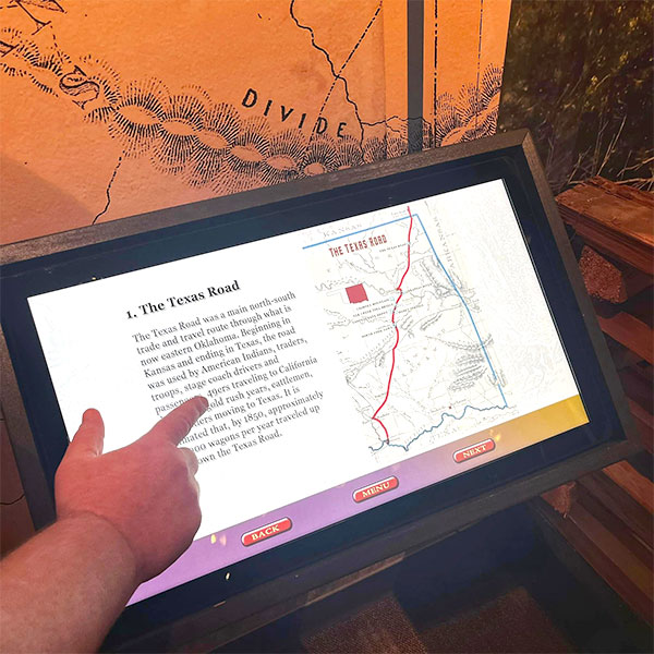 A hand points to an touchscreen about the Texas Road.