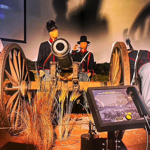 Male mannequins depicting Union soldiers stand behind a large brass cannon. 